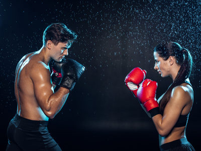 120874861-vue-latérale-de-deux-boxeurs-en-gants-de-boxe-s-entraînant-ensemble-sous-des-gouttes-d-eau-sur-fond